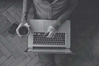 man drinking coffee and using a laptop